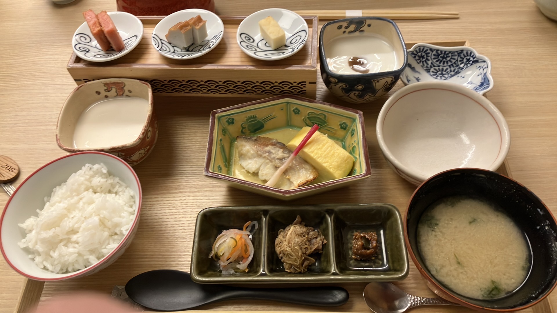 一つのお盆に乗ってやってきた。左上に横長の台があって三皿練り物系が並んでいる。その右側にはヨーグルト、取り皿。上から2列目は左から順に豆腐、本日の焼き魚(鯛っぽい色)と厚焼き、磯鍋用の取り皿。いちばん下の列はご飯、なますや牛しぐれなど、味噌汁。